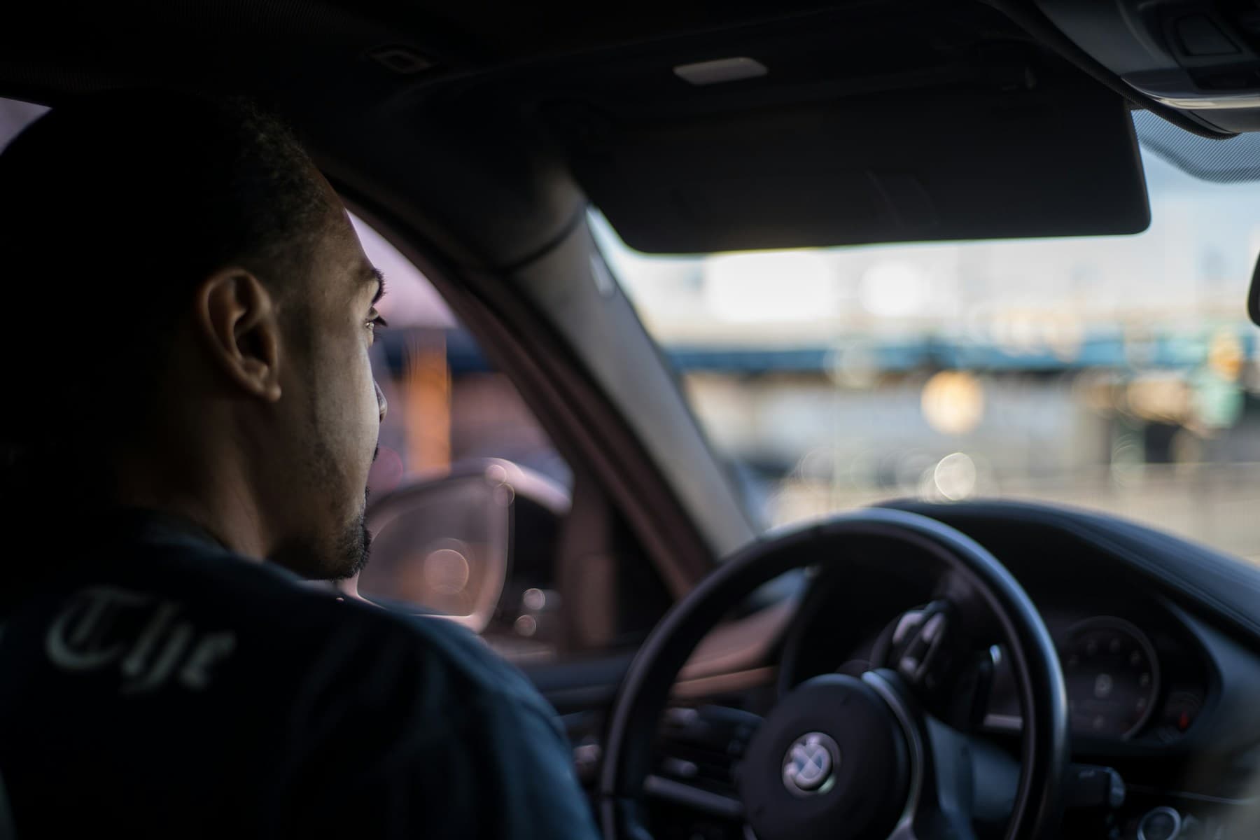 A chauffeur at the wheel of a waiting car