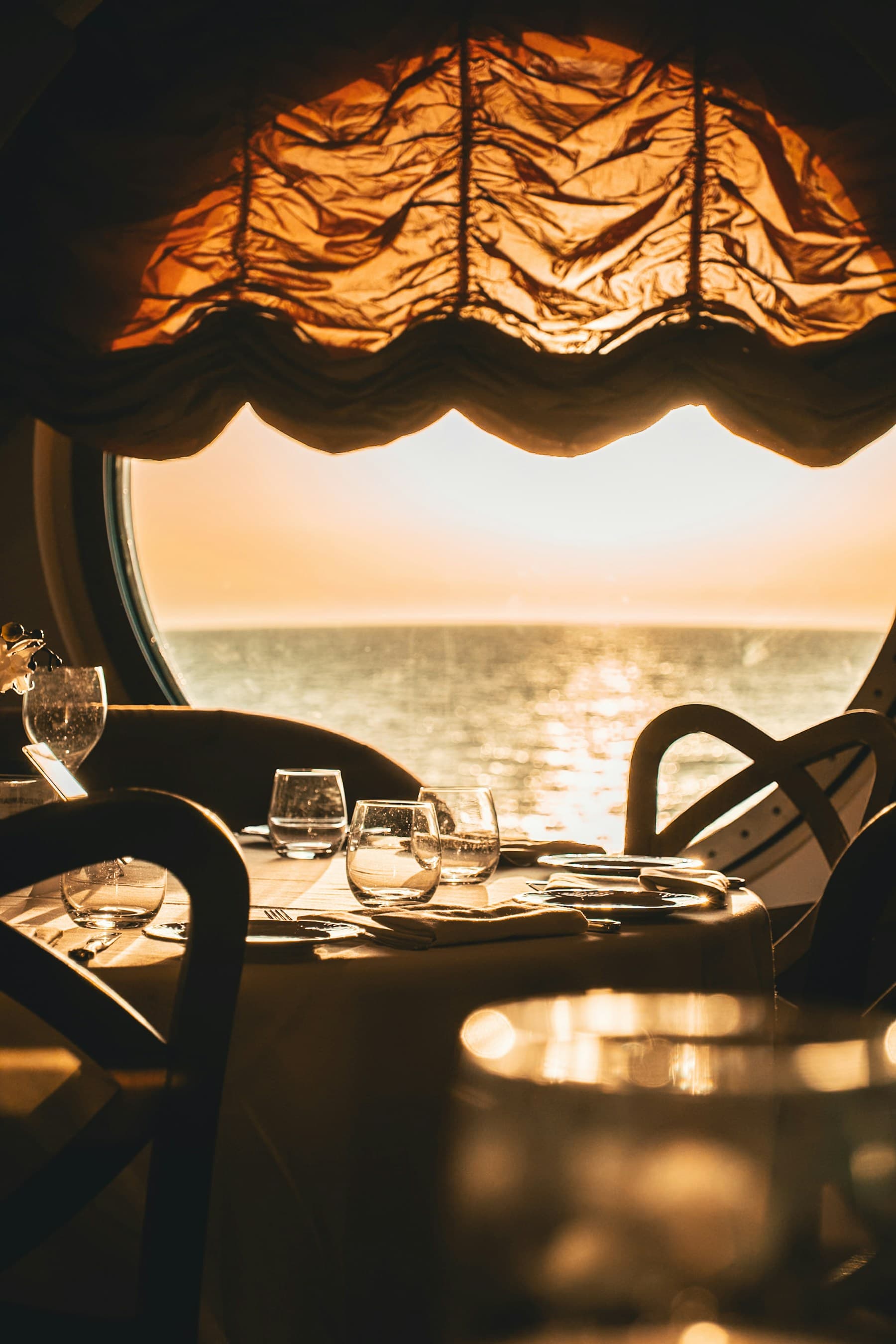 A table set for lunch beside a yacht window looking out to sea