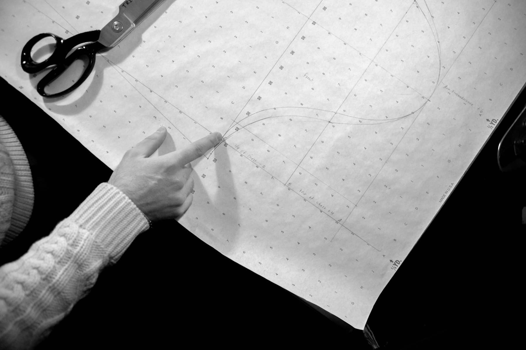 A tailor's hand tracing a pattern drawn on paper
