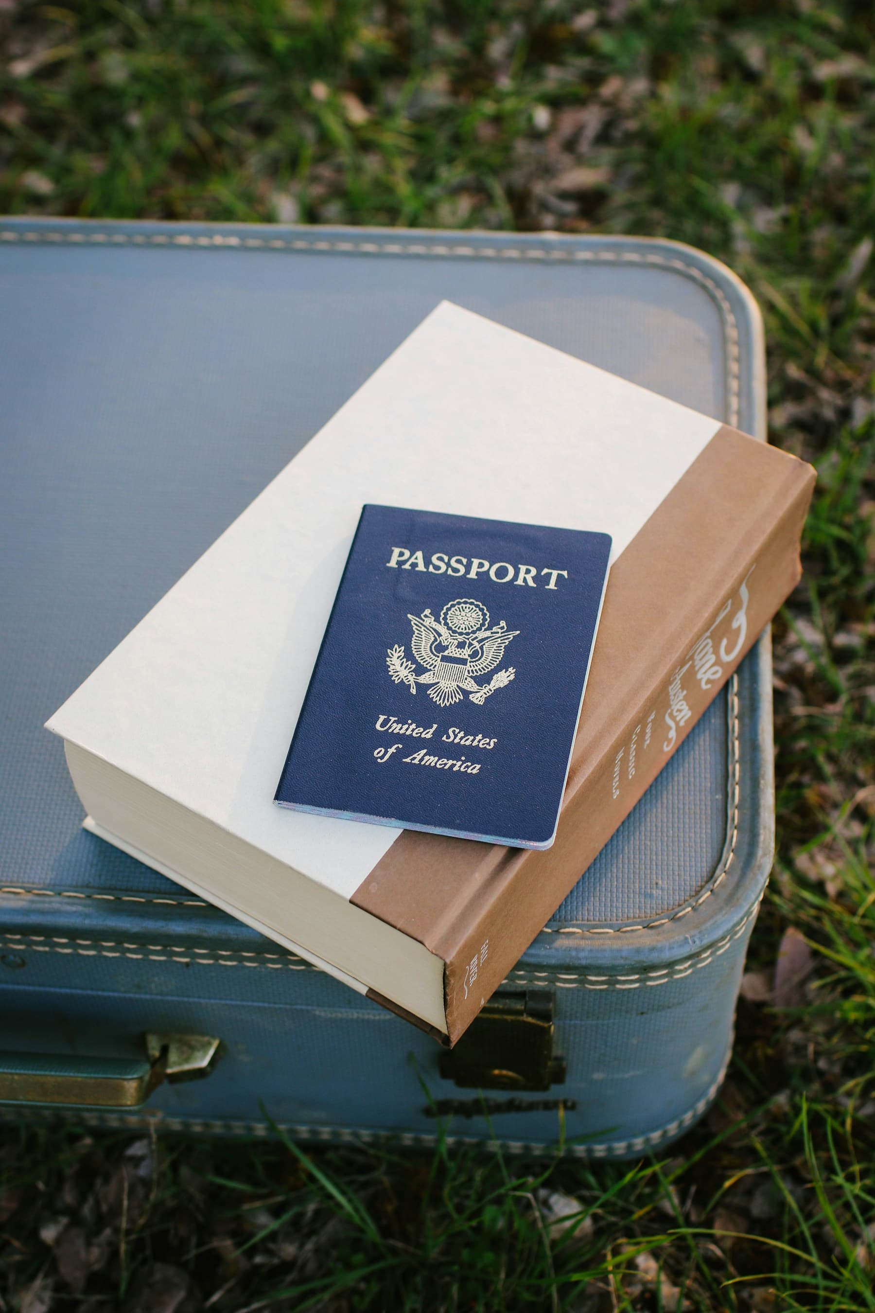 A passport resting on a book on top of a travel case